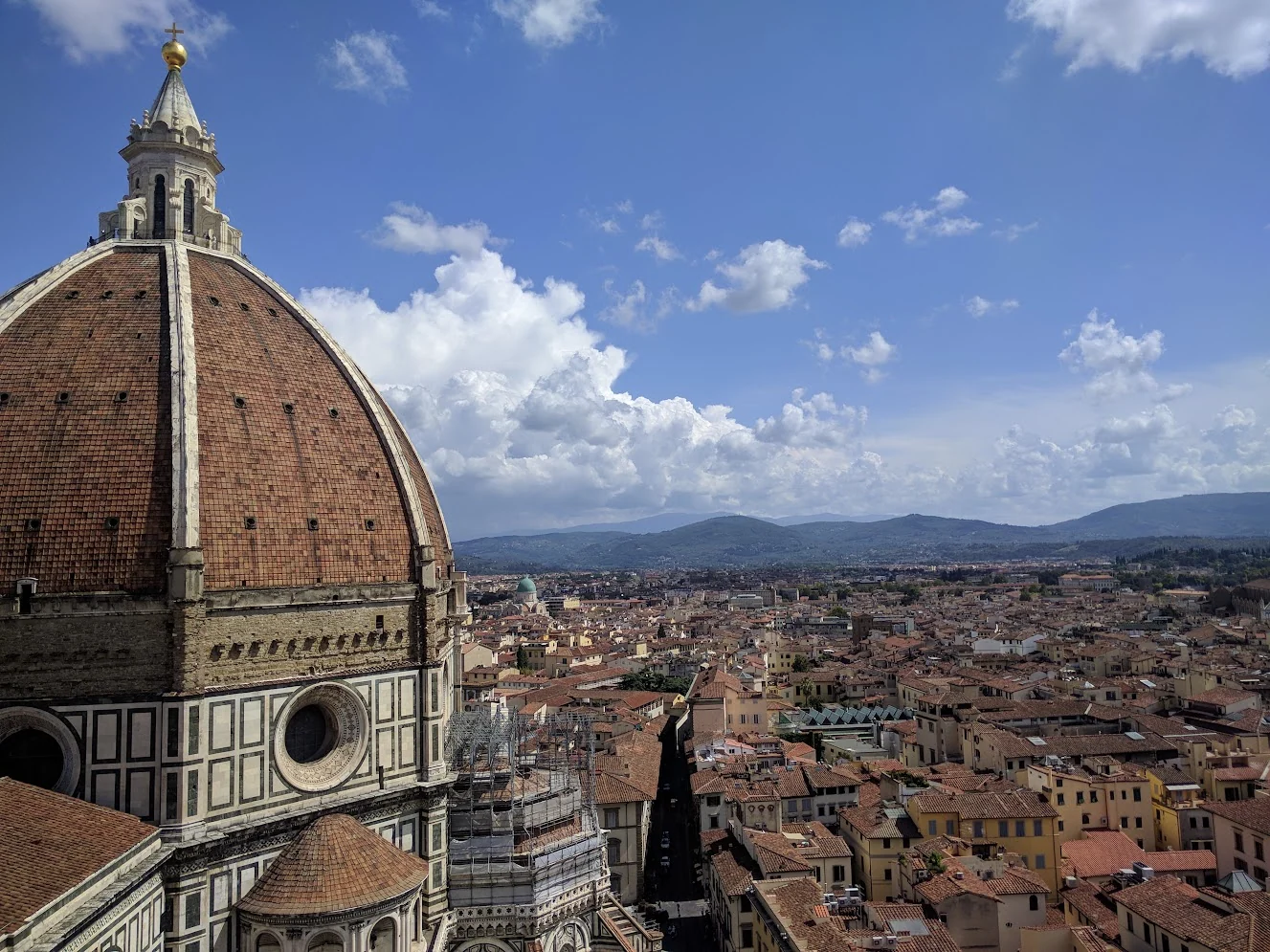 The tiled dome of Florence Cathedral fills the foreground above the city's terracotta roofs and distant hills.
